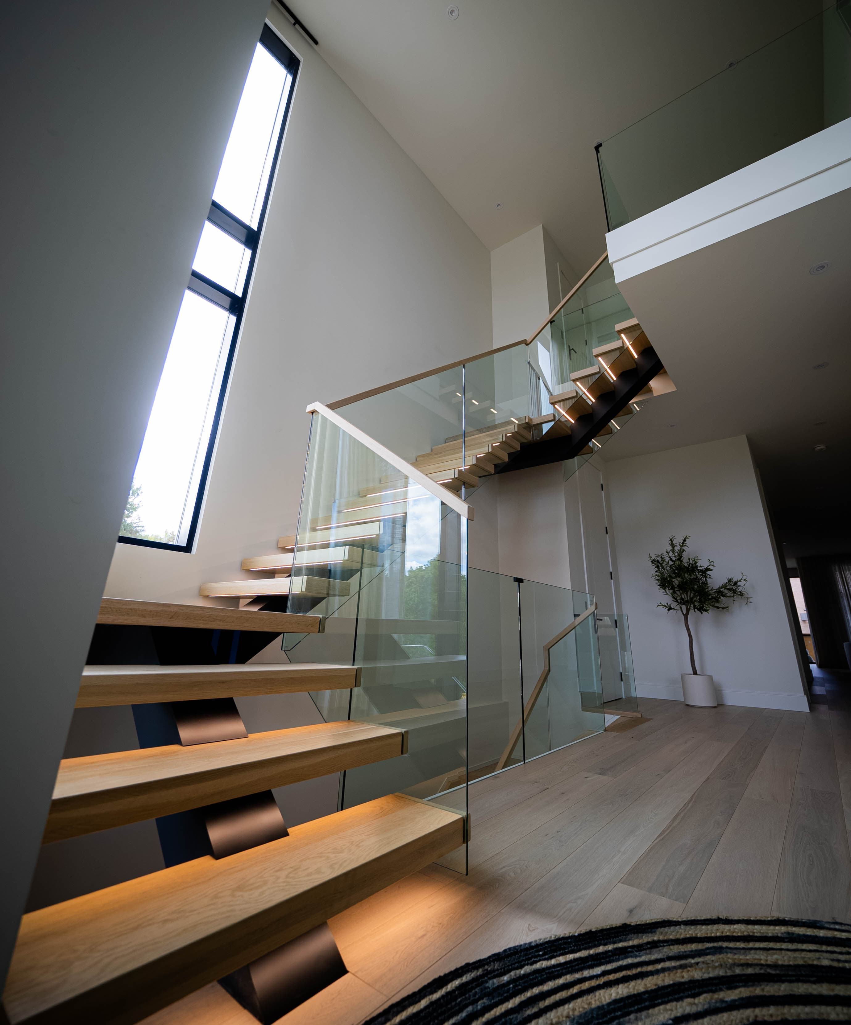 Modern luxury staircase with floating wooden steps - dramatic upward angle