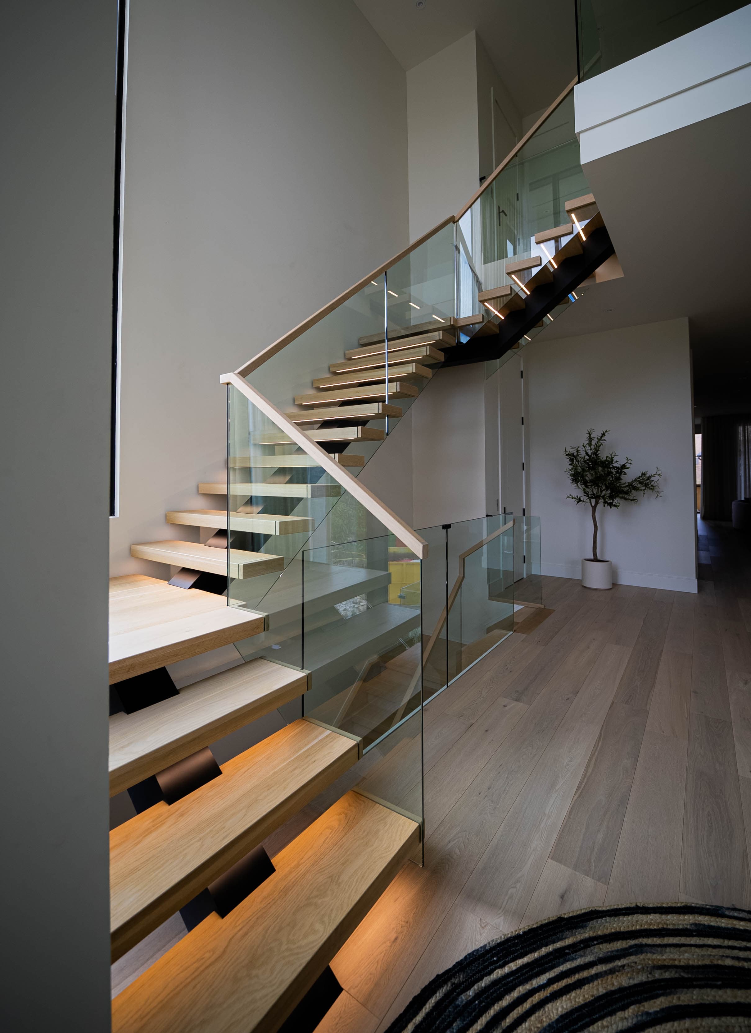 Modern luxury staircase with floating wooden steps and glass railings - front view